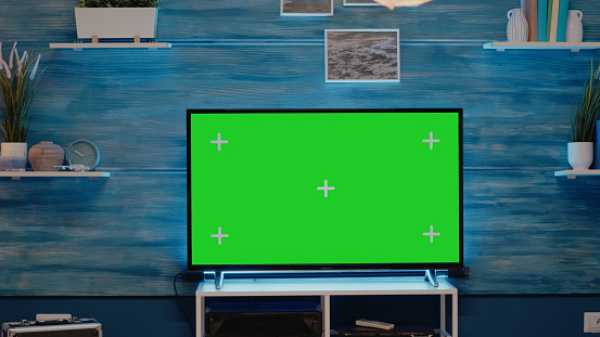 Nobody in flat with green screen tv display used to design chroma key with isolated media. Empty room with copy space and mockup template for modern background and technology
