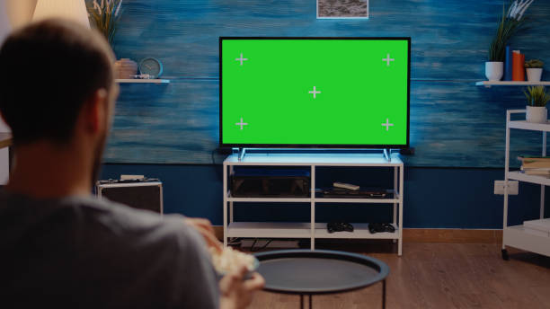 istock Man watching green screen TV in living room 1701862819