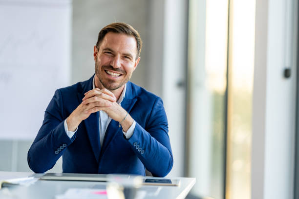 Mid adult businessman at work looking at camera with smile. stock photo