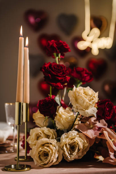 istock Luxury candlelight dinner setup for couple on Valentine's day. Romantic date. Setting table in restaurant. Location decoration red flowers, decor candles for surprise marriage proposal. Closeup detail 1701907435