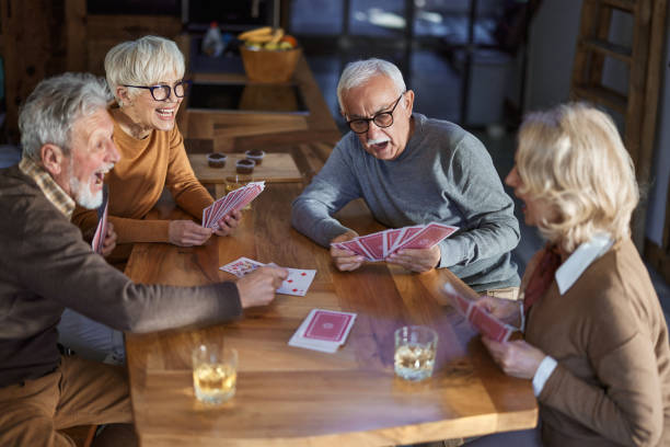 istock Happy senior friends enjoying while playing cards at home. 1701909659