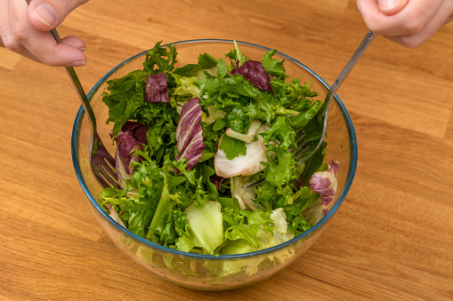 Healthy diet mixed salad with dressing in a glass bowl
