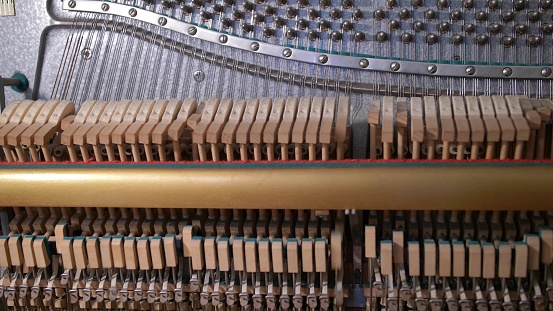 Upright Piano Mechanism Hammers Striking Strings When Song is Played by Musician