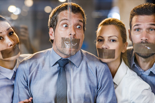 Group of business people with duct tapes on their mouth in the office.