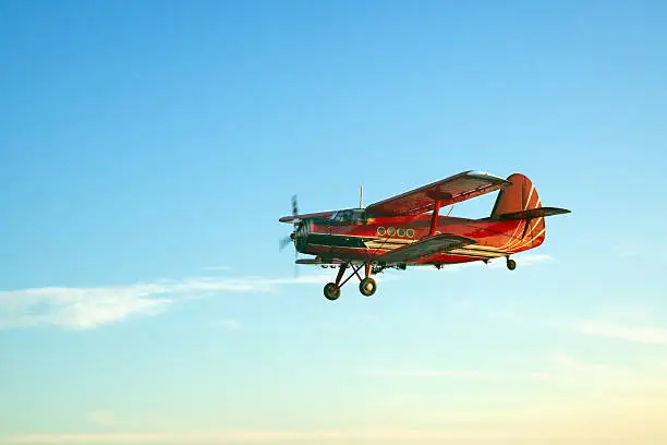 Retro red aircraft flying against blue sky