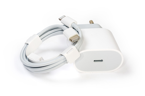 White charger with USB Type-C output socket for batteries charging of portable electronic accessories and appropriate cable, close-up on a white background