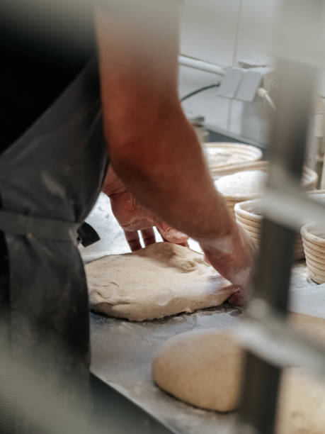 istock Baker molds a loaf of bread in a bakery. Baker's hands at work 1701957364