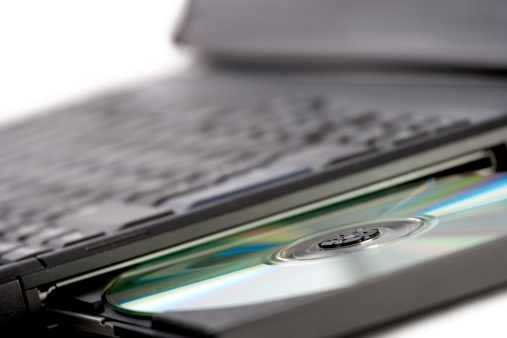 Tablet, keyboard, books, notepad, reading glasses, ear buds, and pens on workspace