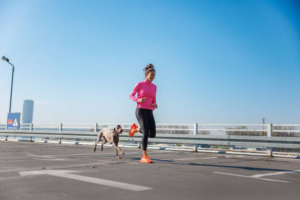 istock Active woman running with her dog on empty parking garage under the clear sky 1701967224