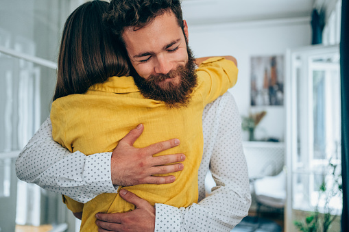 Shot of a young couple embracing each other at home. Coworkers hugging each other together again in the office. Colleagues hugging and celebrating in the office.