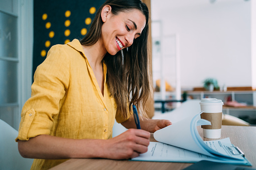 Shot of an adorable smiling businesswoman making notes on a clipboard inside of the office.