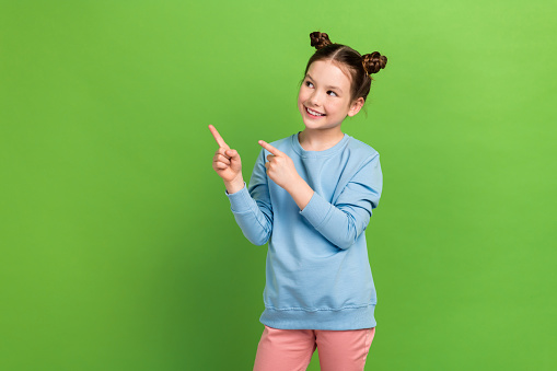 Photo portrait of small girl promoting empty space novelty direct fingers look mockup ads adv isolated green color background.