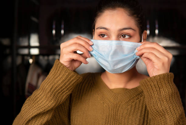 istock Woman wearing protective face mask at home. 1702016649