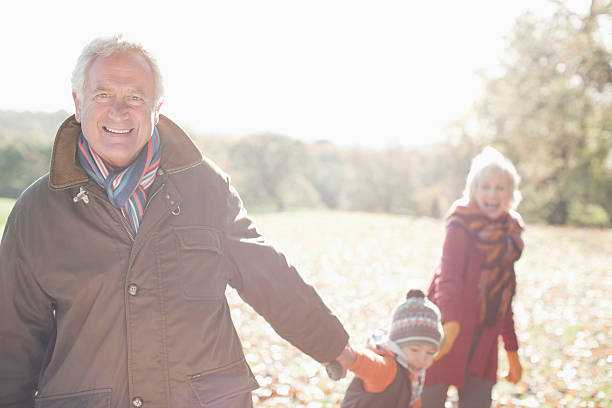 grands-parents et petit-fils jouant dans le parc - generation gap multi generation family vertical holding hands photos et images de collection