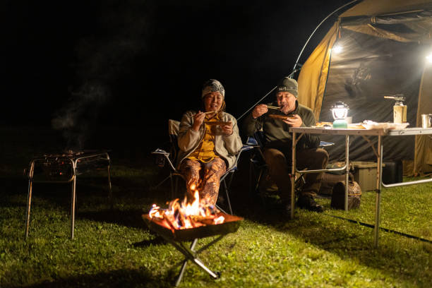 Japanese woman and Caucasian man eating their dinner at camp together.