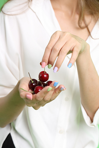 The Asian woman holding berry fruit in the hand on the yellow background.