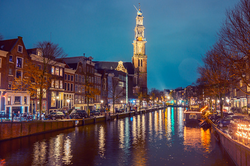 Amsterdam Prinsengracht with the illuminated Westerchurch tower at night with a christmas atmosphere.