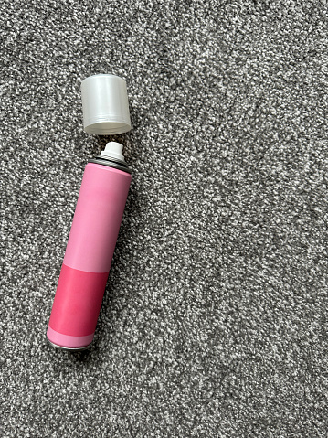 Pink spray can on grey carpet