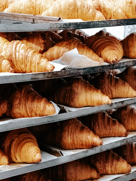 Freshly baked croissants on baking sheets on a rack in a bakery