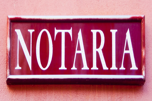 Notary office sign in spanish language hanging from red building facade.León province, , Spain.