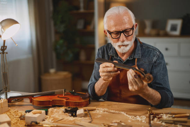 istock Senior carpenter craftsman making violin instrument 1702076200