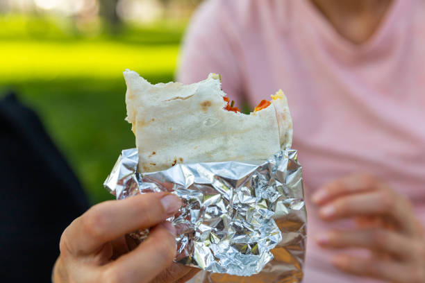 屋外で食べ物を扱う手の接写。削除ピタを持つ女性の手。屋台のコンセプト - meat handling ストックフォトと画像