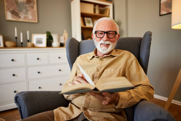 istock Elderly man reading a book at home 1702084244