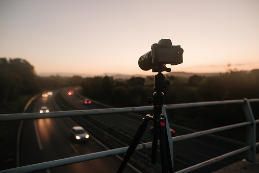A DSLR camera on a tripod over a highway at night