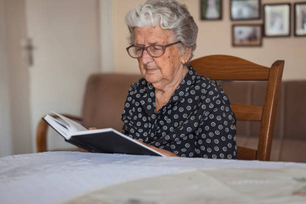istock Serious old woman reading a book at home 1702089619