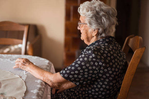 istock Elderly woman sitting at the dining table alone at home 1702090120