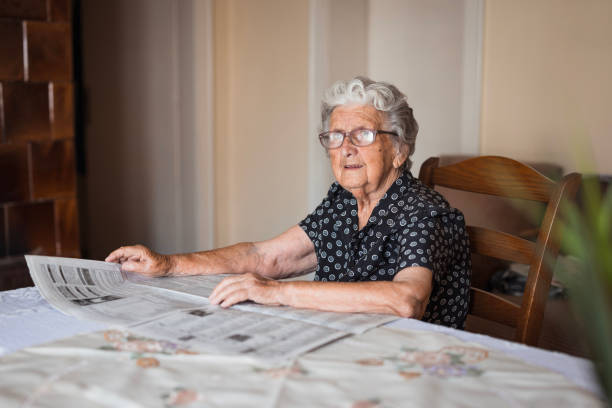 Serious mature woman with newspapers at home