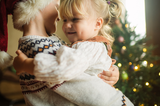 istock Happy children hugging near Christmas tree at home 1702105155