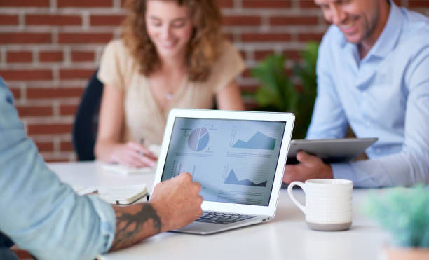 businessman using laptop computer meeting with colleagues discussing financial graph data on screen