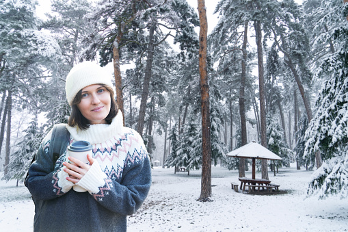 Woman with a cup of hot drink on winter snowy background.