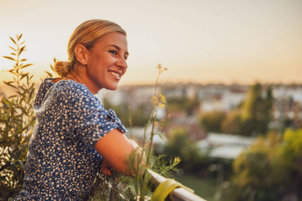 istock Woman enjoys  standing on her balcony at sunset 1702136670