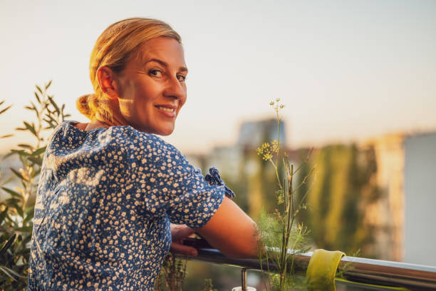 istock Woman enjoys  standing on her balcony at sunset 1702136671