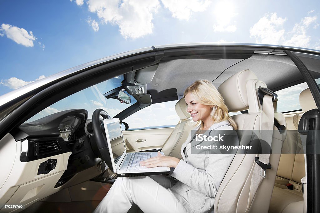 Linda mulher loira sentando em seu carro e usando o laptop. - Foto de stock de Cabelo Louro royalty-free