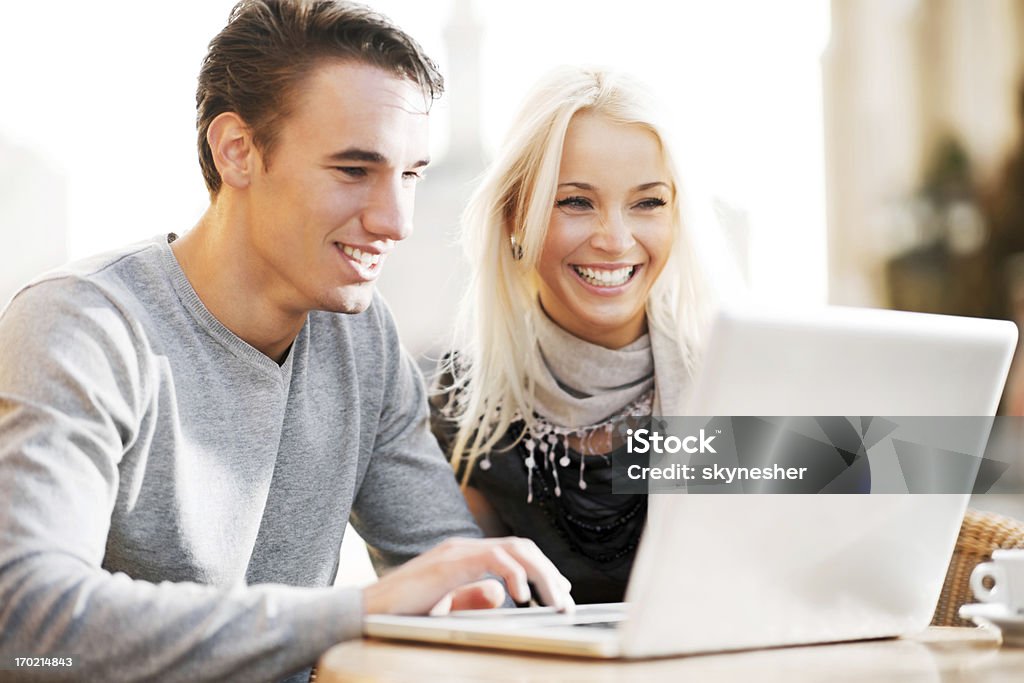 Beau couple assis dans un café et utiliser un ordinateur portable. - Photo de A la mode libre de droits