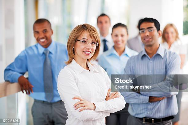 Businesswoman In White With Colleagues In Blue Stock Photo - Download Image Now - Organized Group, Business, Crowd of People