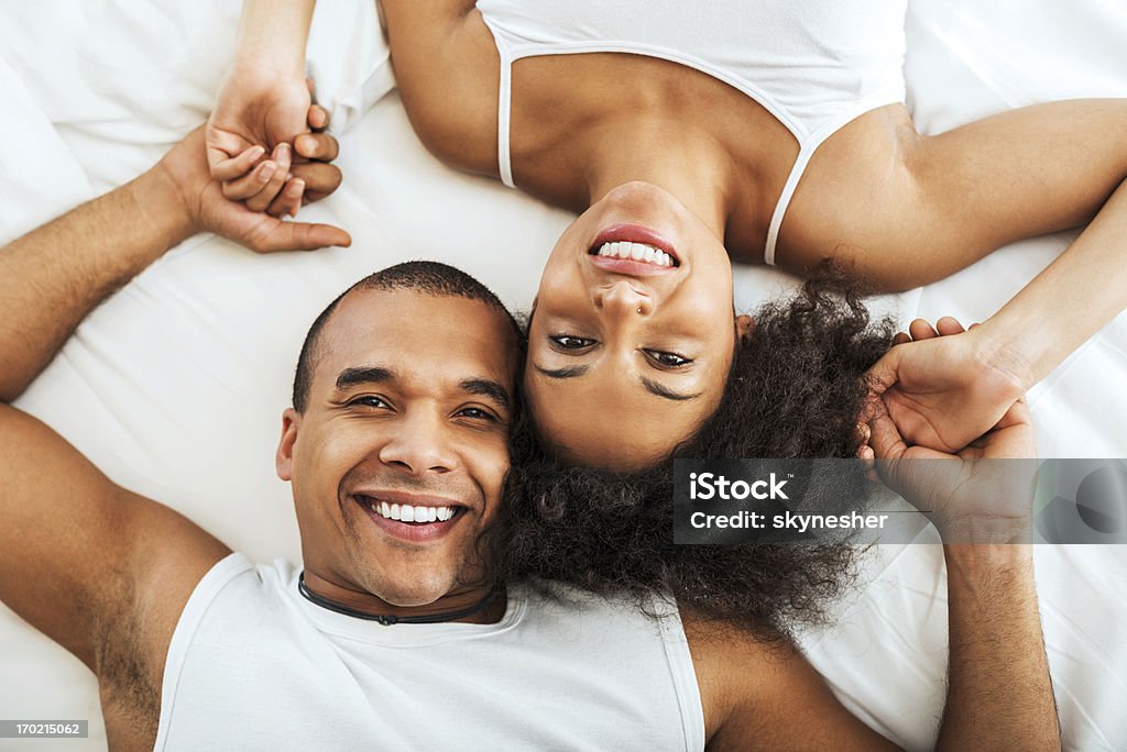 Alegre pareja de yacer en la cama. - Foto de stock de 30-39 años libre de derechos