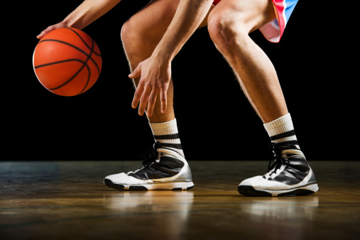 Basketball player is dribbling on the basketball court.   