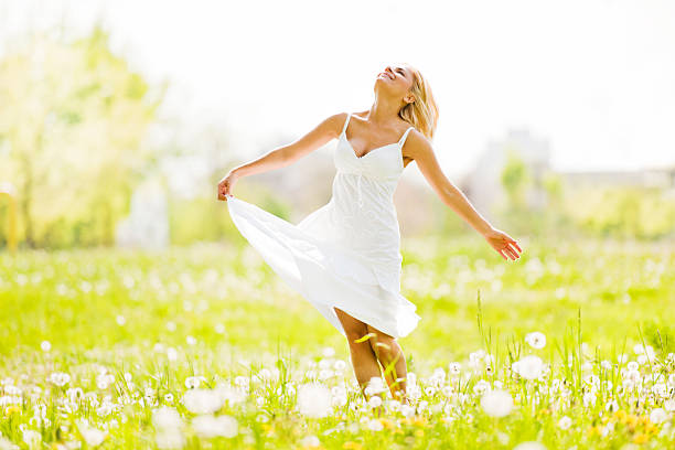 Smiling young woman standing in the field surrounded by lush greenery.  She is looking up.   