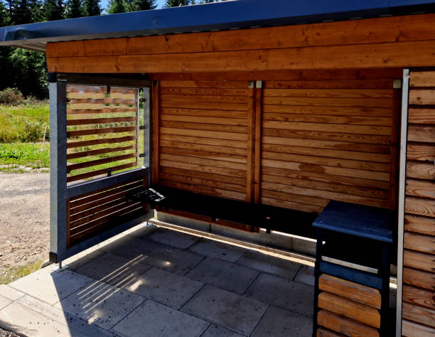 istock pergola roof with bus stop. combined with bin sorting. plastic, paper, glass separated into colored bins. wooden slats, blue sky, clouds 1702166895