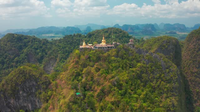 Aerial view Tiger Cave Temple, Buddha on the top Mountain with blue sky of Wat Tham Seua, Krabi,Thailand. Aerial view 4K.