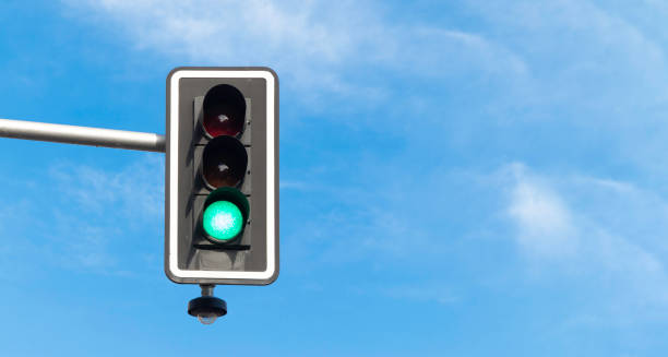 istock Traffic light on green, with blue sky and clouds on the background. Copy space 1702174998
