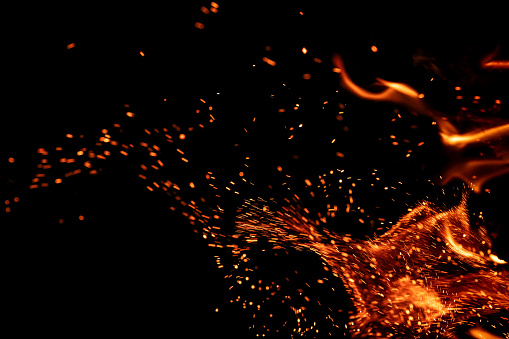 Burning fire with sparks on black background. Can be used as design element in screen add mode or as a text / product placement background.