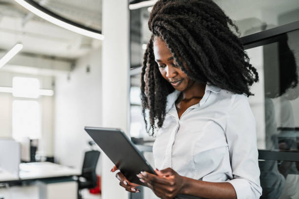 istock Beautiful black woman using digital tablet for communication and project work in modern office 1702180651