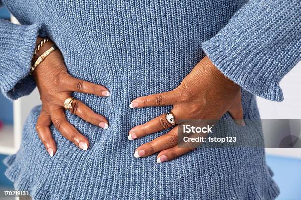 Senior African Descent Woman Grabs Lower Back In Pain Stock Photo - Download Image Now