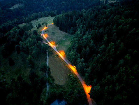 the path through the mountains from a height, is lit by lamps at regular intervals in the bend. illumination is the orange color of the spectrum. evening landscape intimately tender, friendly, eco