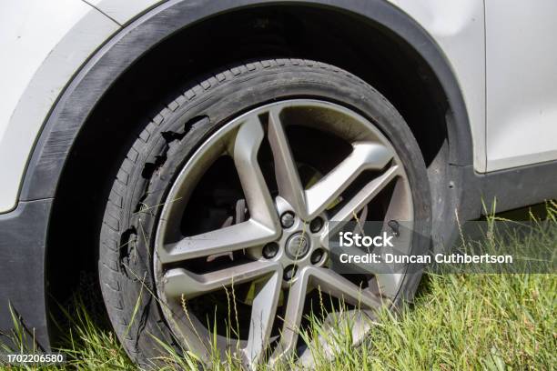 A Car With A Flat Tyre After A Large Blow Out On The Highway Showing A Large Slit In The Tyre At The Side Of The M25 Motorway In London In The Uk Stock Photo - Download Image Now